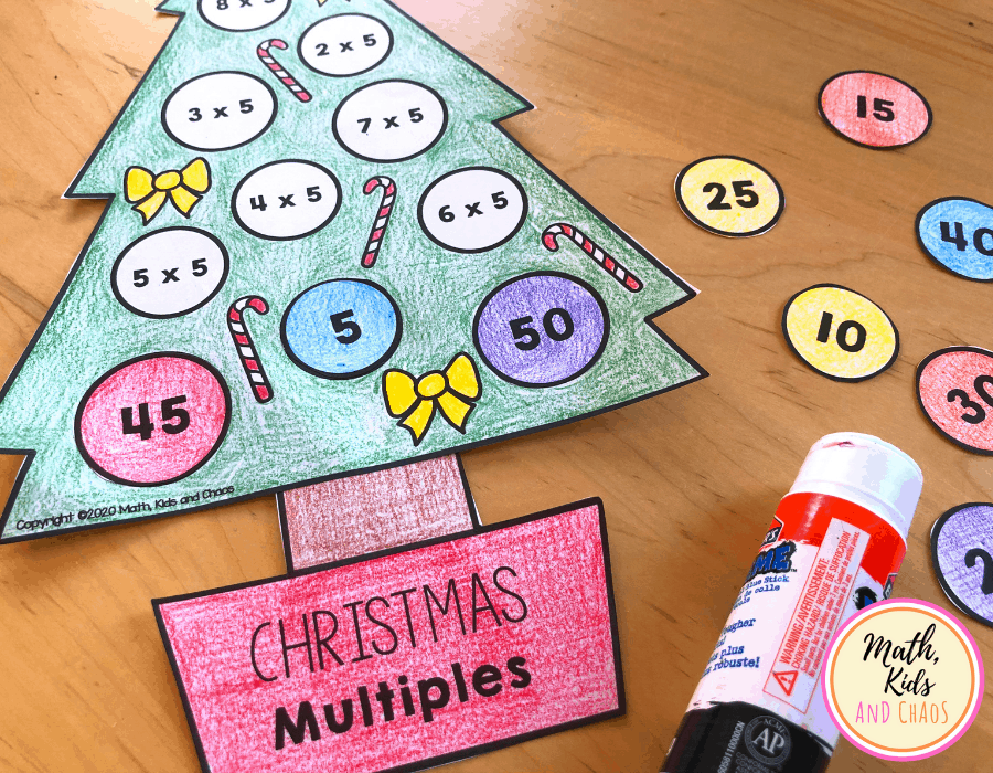 Gluing baubles on Christmas tree craft. Paper tree with some baubles already attached next to a glue stick on table top.