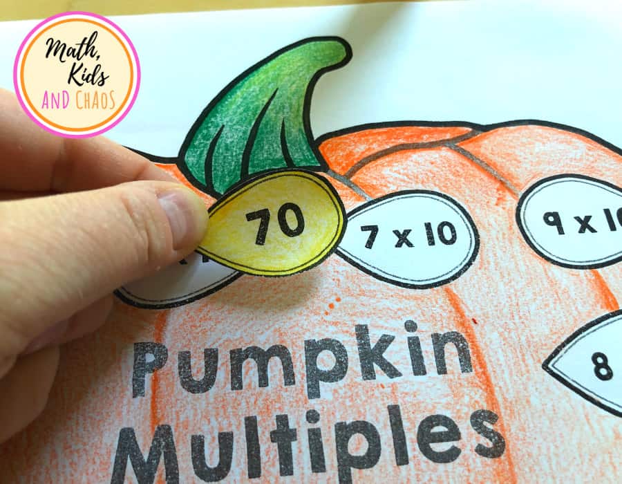 Pumpkin seed showing the number 70 about to be stuck onto the space showing 7 x 10.