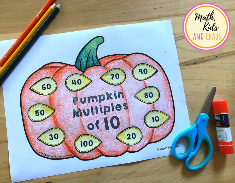 Pumpkin picture with seeds showing numbers that are multiples of 10. Glue stick, scissors and pencil crayons on the table.