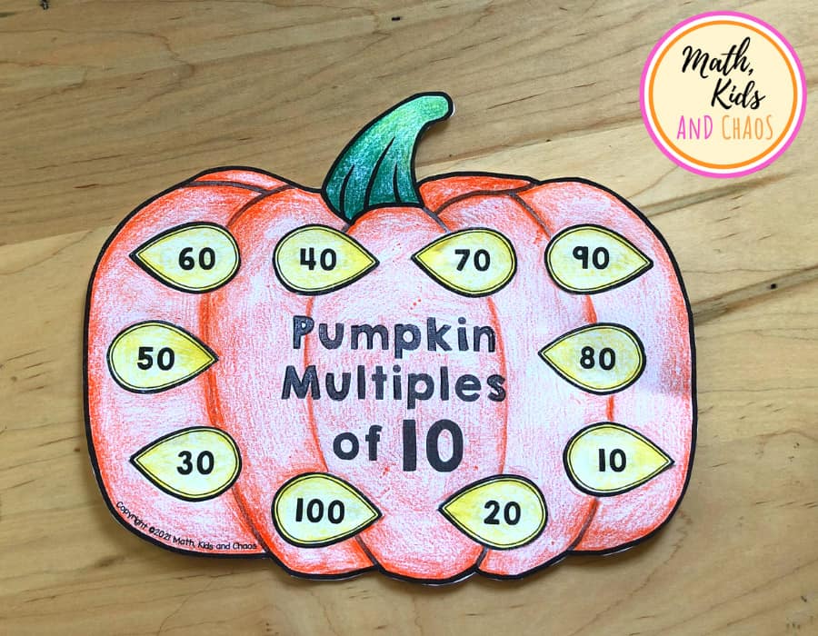 Completed Pumpkin math craft. Paper pumpkin coloured orange with seeds that each show numbers that are a multiple of 10.