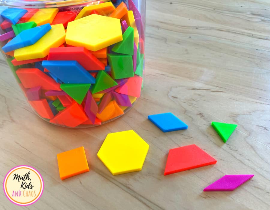 six different pattern block shapes on table top in front of a tub of blocks